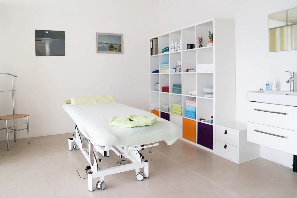Heller Behandlungsraum mit Liege und Regal